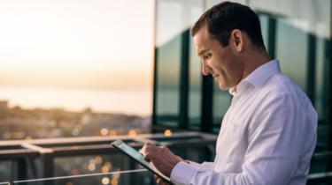 Exportateur étudie tablette sur balcon donnant sur les toits de la ville