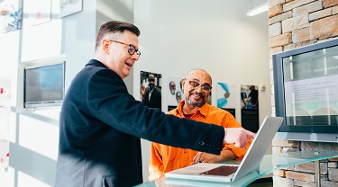 Deux hommes regardent un écran d’ordinateur.