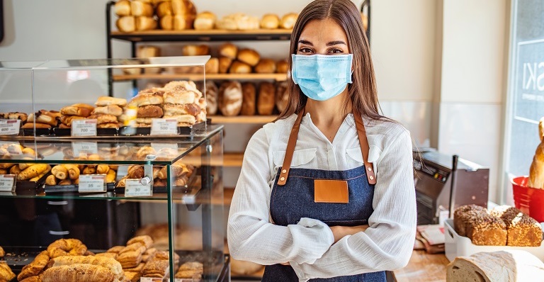 Le propriétaire de la boulangerie porte un masque en magasin.