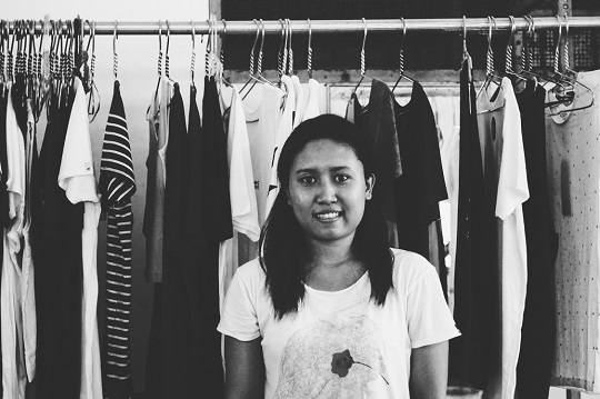 Balinese female factory worker stands in front of Ekumenik clothing rack