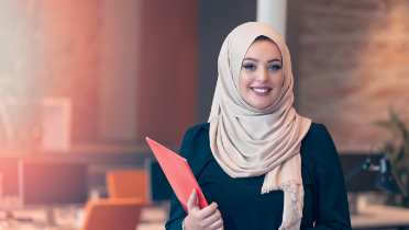 Une femme d’affaires portant le hijab tient des dossiers dans un bureau.
