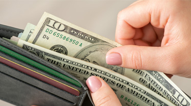Main d’une femme tenant un portefeuille contenant des dollars américains