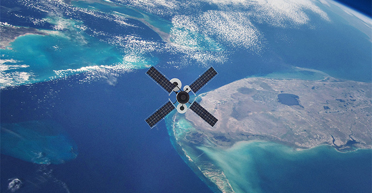 Satellite en orbite autour de la Terre au-dessus de l’océan et des côtes.