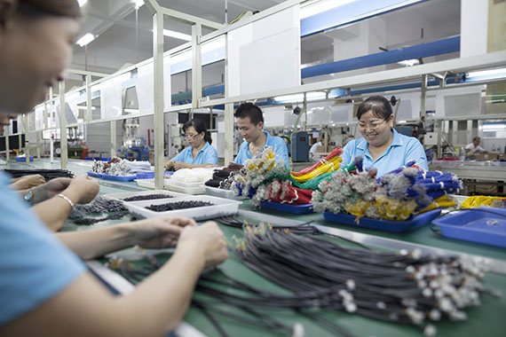 Image of people working to manufacture parts for the information and communications technology industry, representing trade.