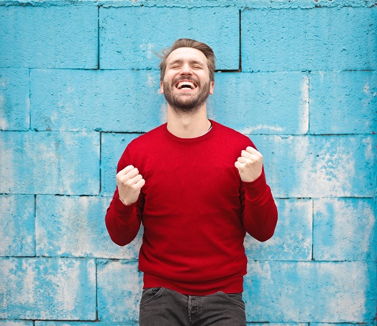 Man in red sweater celebrating a win.