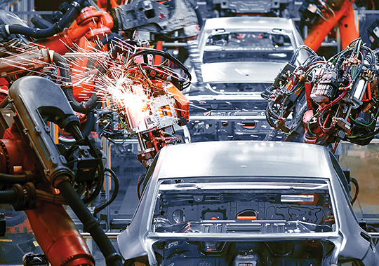 Des bras robotisés assemblent une automobile dans une chaîne de montage industriel.